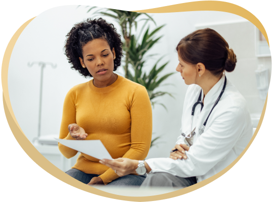 dot-physicals-hero-img Healthcare professional in a white coat with a stethoscope discusses a clipboard with a patient wearing a mustard sweater in a clinic setting.